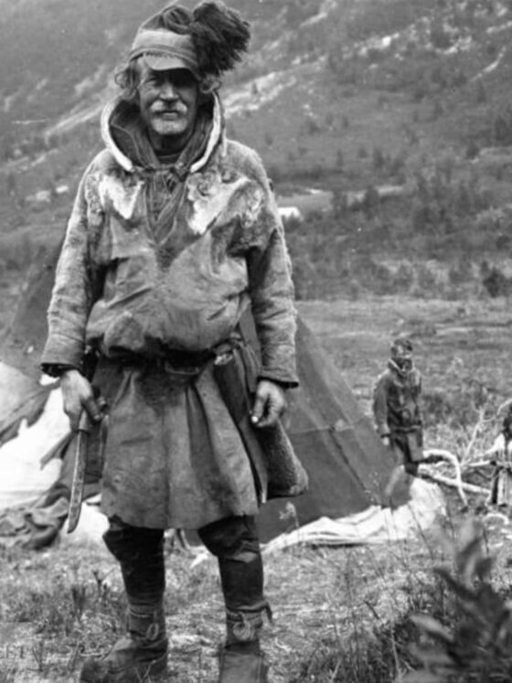 Un Sami de Norvège. Il tient un leuku et à sa ceinture pend l'étui typique avec un boîtier en bois.